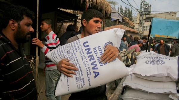 A man clutches a large sack of flour labeled UNRWA during distribution efforts in Deir al-Balah, Gaza, on November 2, 2024. The Turkish Disaster and Emergency Management Presidency (AFAD) has provided flour amidst a food crisis caused by o<em></em>ngoing Israeli attacks. 